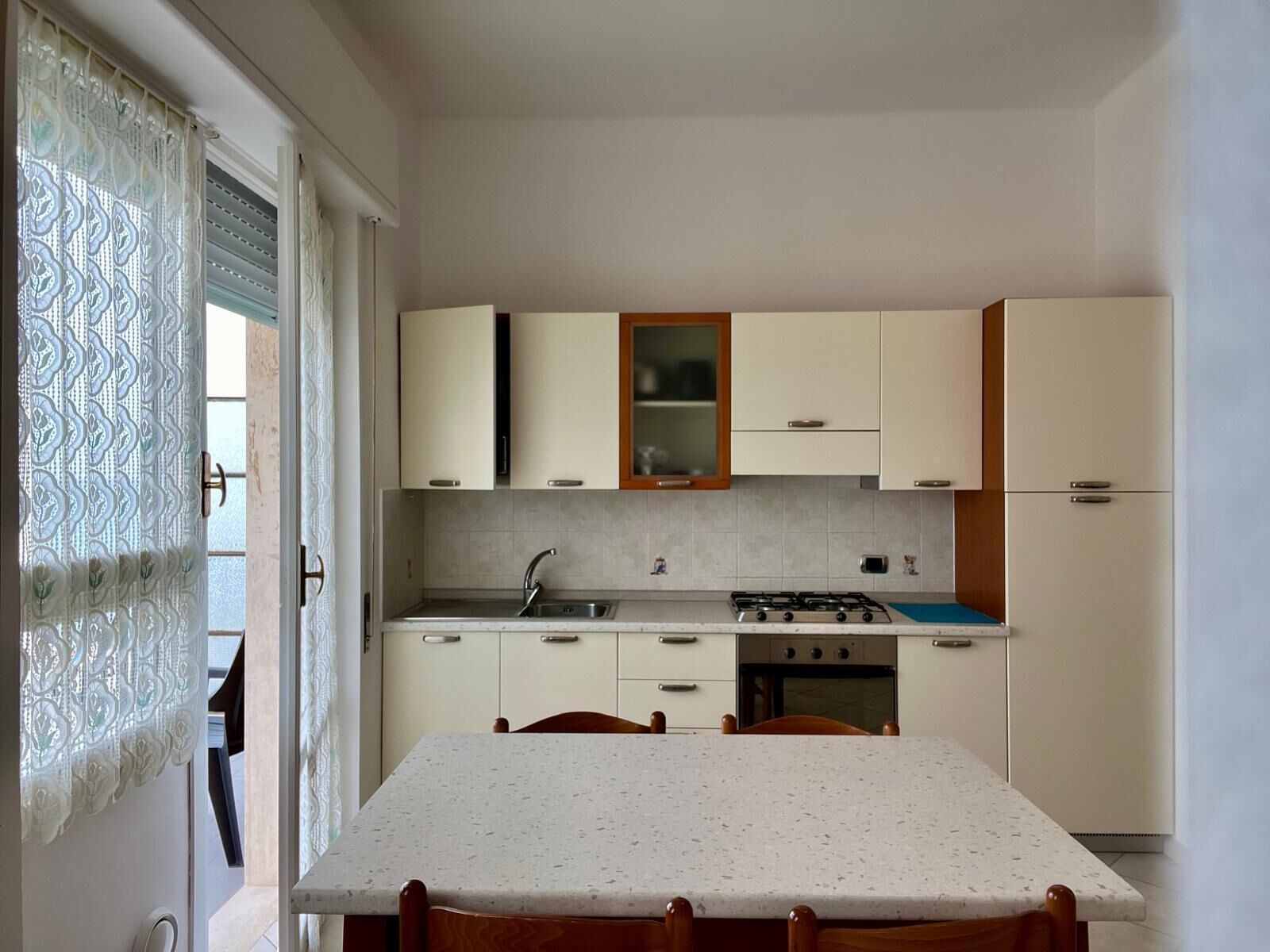 Une cuisine de taille réduite, équipée d’une cuisinière à gaz, d’un évier et de placards.