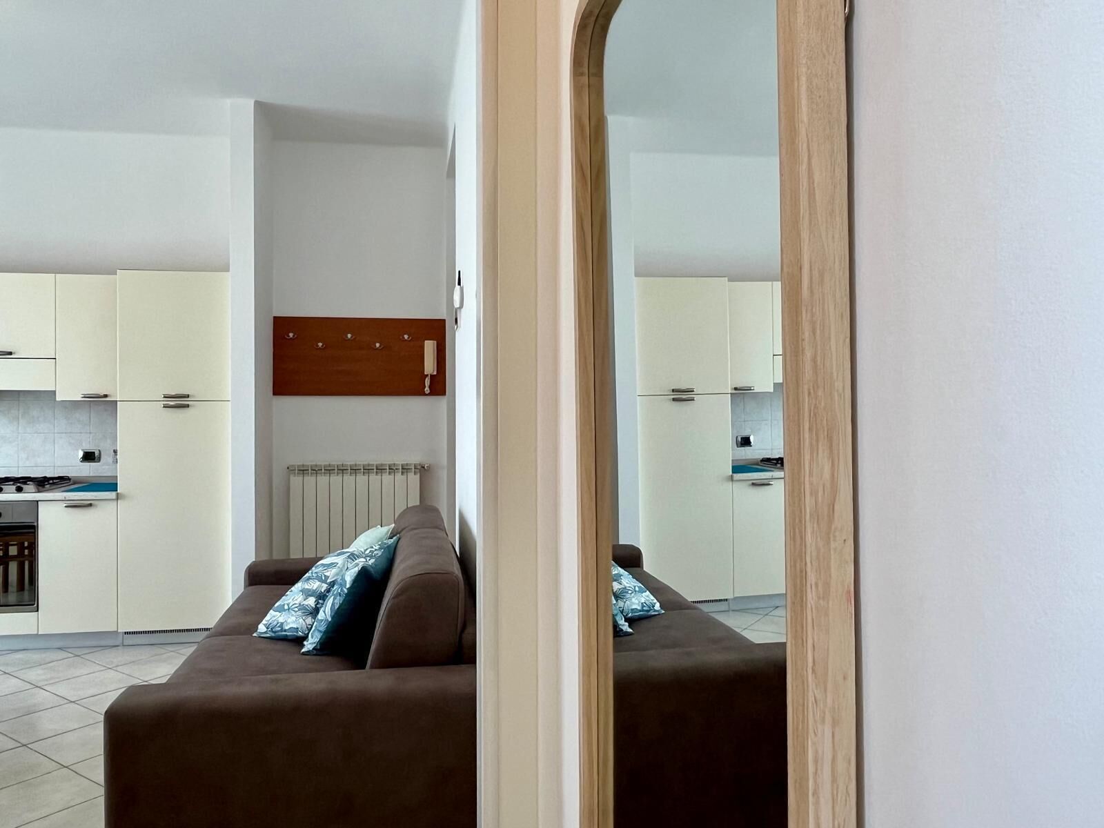 Ein modernes Apartment mit Wohnzimmer, Küche und einem großen Spiegel.