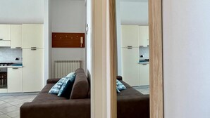A modern apartment with a living room, kitchen, and a large mirror. - Appartamento sul Lungomare by Tempovacanza (Marina di Andora)