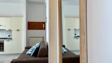 Ein modernes Apartment mit Wohnzimmer, Küche und einem großen Spiegel.