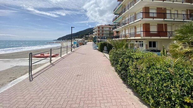 A seaside promenade with a paved walkway, beachfront buildings, and a clear sky. - Appartamento sul Lungomare by Tempovacanza (Marina di Andora)