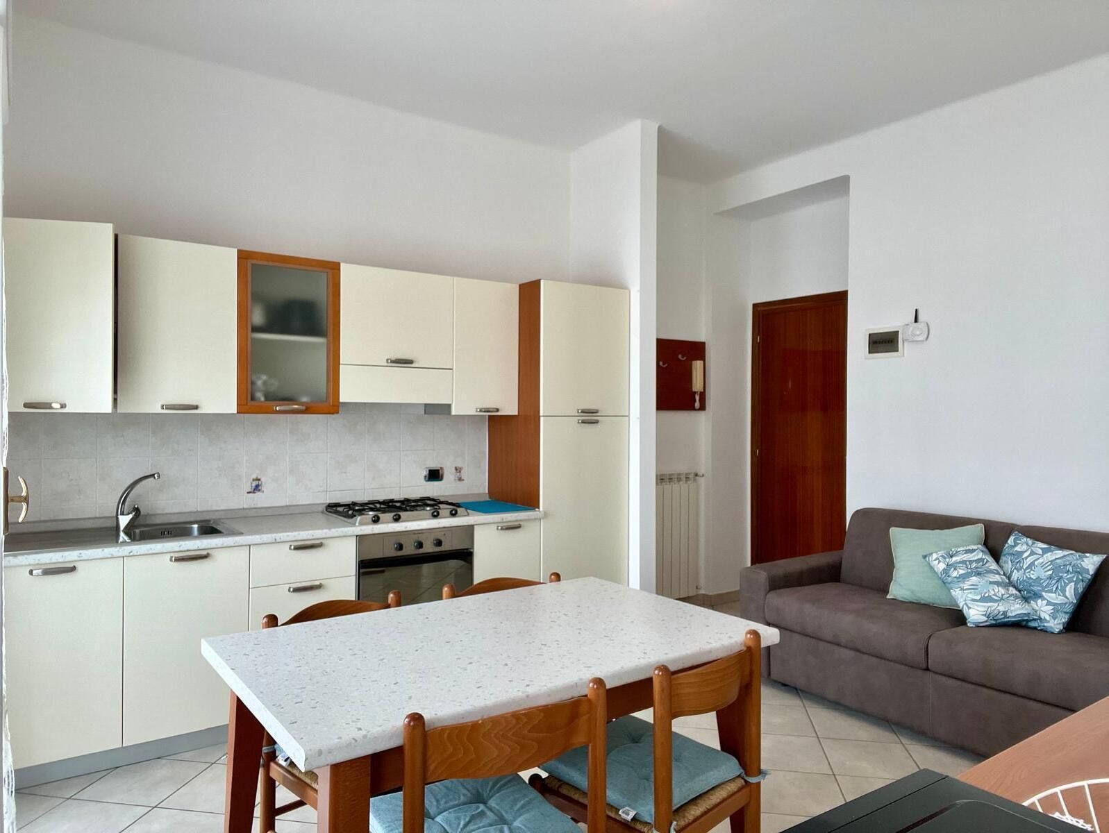 Een compacte keuken met een eettafel, stoelen, een bank en een klein zithoekje.