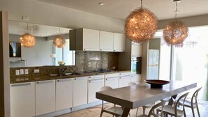 Una cocina moderna con armarios blancos, encimera de granito y dos lámparas colgantes.