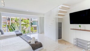 Una habitación de hotel moderna con una cama grande, un televisor y un balcón con vistas a zonas verdes.