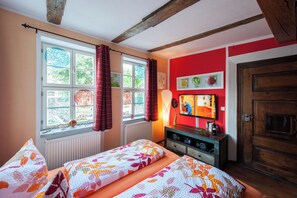 A bedroom with a bed, a TV, and a window with curtains.