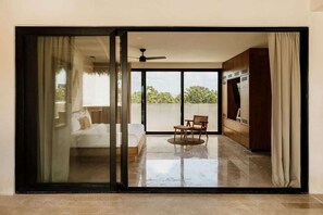 A modern room with a sliding glass door leading to a balcony, a ceiling fan, and a bed with a white duvet. - Itza Maya Penthouse Sunny Rooftop Aldea Zama (Tulum)