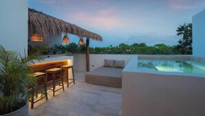 Une terrasse sur le toit dotée d’une piscine, d’un espace salon et d’une structure recouverte de chaume.
