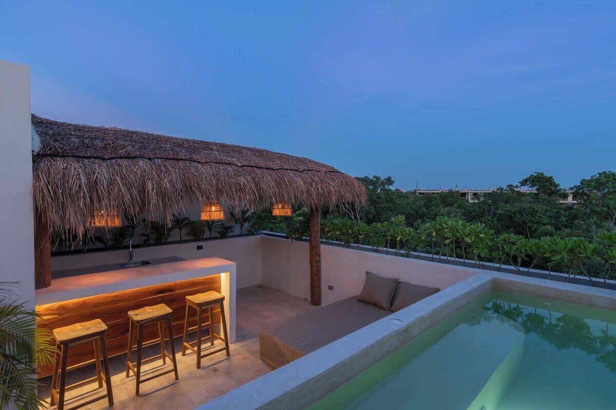A poolside area with a bar, seating, and a thatched roof structure.