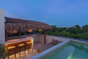 A poolside area with a bar, seating, and a thatched roof structure.