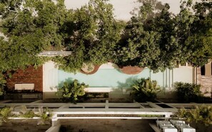 A modern building with a central courtyard, surrounded by lush greenery and a white fence.
