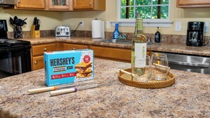 A kitchen counter with a box of Hershey's s'mores cookies, a bottle of Seagram's whiskey, and two glasses on a woven coaster. - Lakefront Treehouse Retreat Minutes from Clemson University! (Seneca)