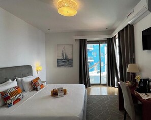 Habitación de hotel con cama, escritorio, silla, lámpara, un cuadro y vistas a un puente.