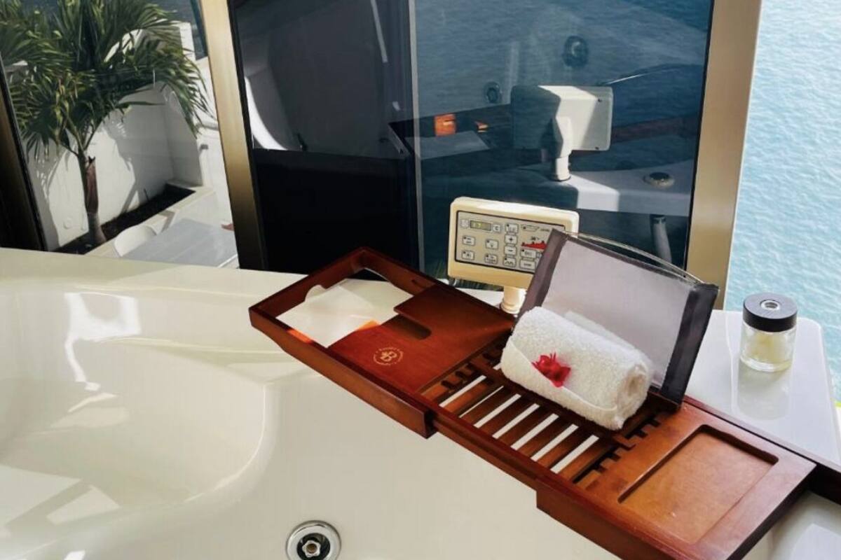 Une salle de bain avec une baignoire, un plateau en bois avec une serviette et un panneau de commande.