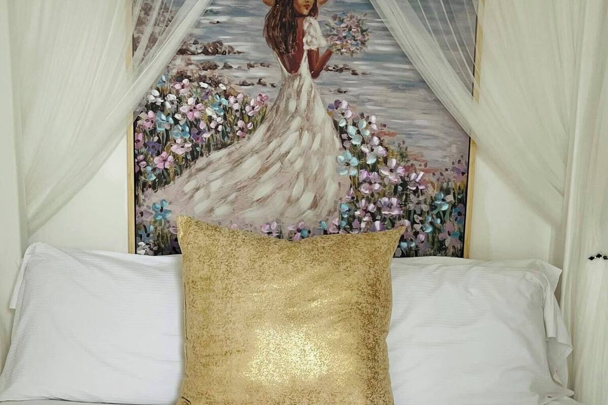 Un lit bien fait, avec du linge de lit blanc, un coussin doré et une étiquette en bois sur une serviette blanche.