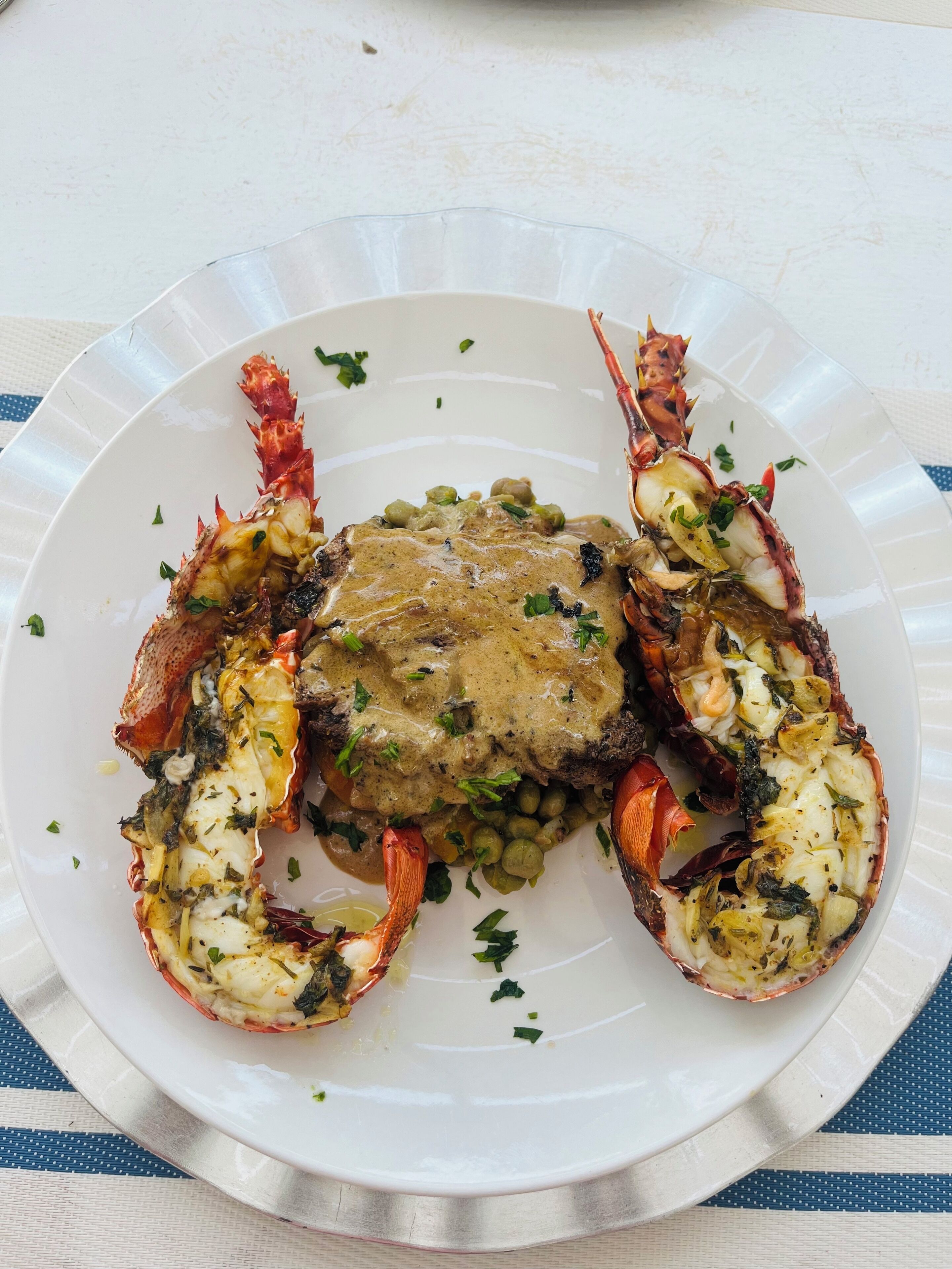 Un plato de langosta sobre un plato blanco, adornado con perejil.