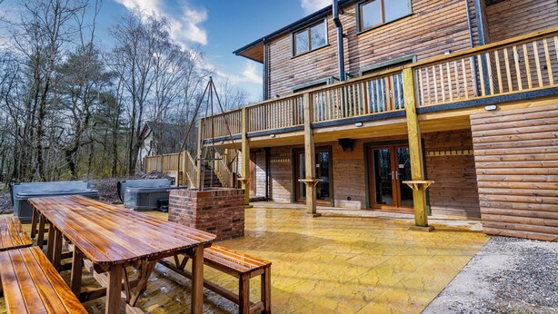 Una cabaña de madera con balcón, mobiliario exterior y chimenea.