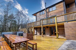 Una cabaña de madera con balcón, mobiliario exterior y chimenea.