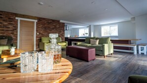 Una sala de estar moderna con una mesa de centro de madera, un sofá verde y un reposapiés rojo.