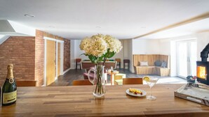 Una sala de estar moderna con una mesa de madera, un florero de flores, una botella de champán y una copa de cóctel.