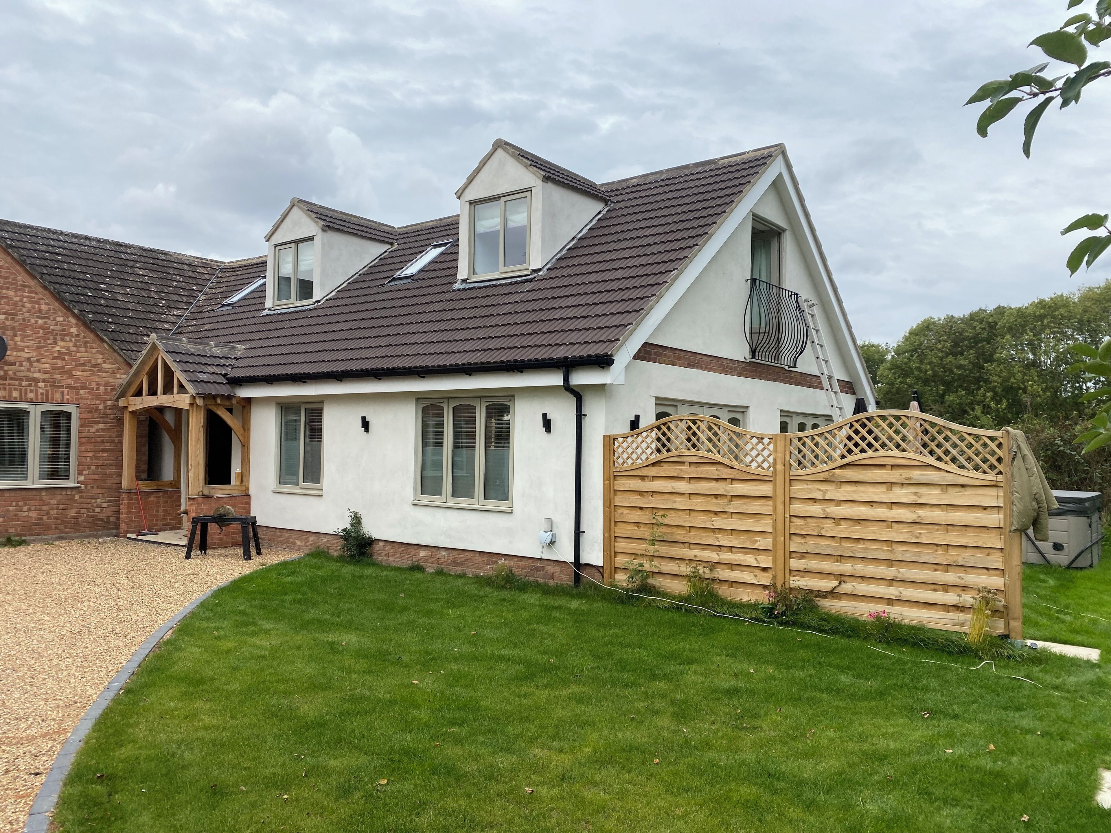 A two-story house with a sloped roof, a wooden fence, and a well-maintained lawn.