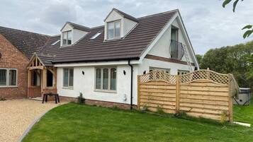 A two-story house with a sloped roof, a wooden fence, and a well-maintained lawn.