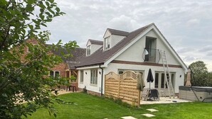 Ein zweigeschossiges Haus mit einem geneigten Dach, einem Holzzaun und einem Rasen mit trittfesten Steinen.