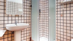 Un baño con ducha, lavamanos e inodoro.
