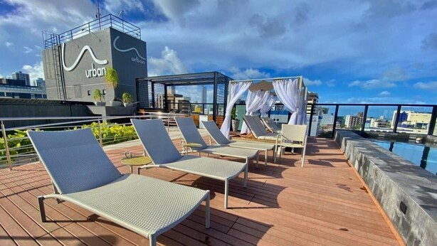 Une terrasse sur le toit avec des chaises longues, une piscine et un bâtiment arborant une enseigne au style « urbain ».