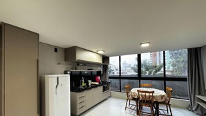 Une cuisine compacte avec un coin repas, de grandes fenêtres et une vue sur le paysage urbain.