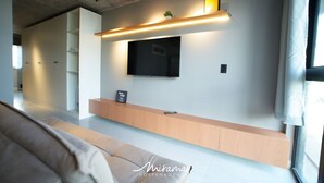 Un salon moderne avec un téléviseur à écran plat fixé au mur, une console en bois et un canapé.