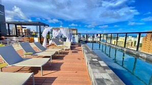 Un espace piscine aménagé sur le toit, avec des chaises longues et une vue sur la ville.