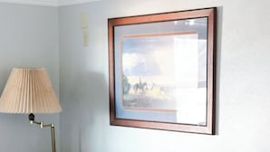 En grå sofa med mønstrede puder, en gulvlampe og et billede i ramme på væggen.