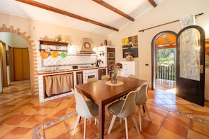 A kitchen with a dining table and chairs, a tiled floor, and a view of the outdoors.