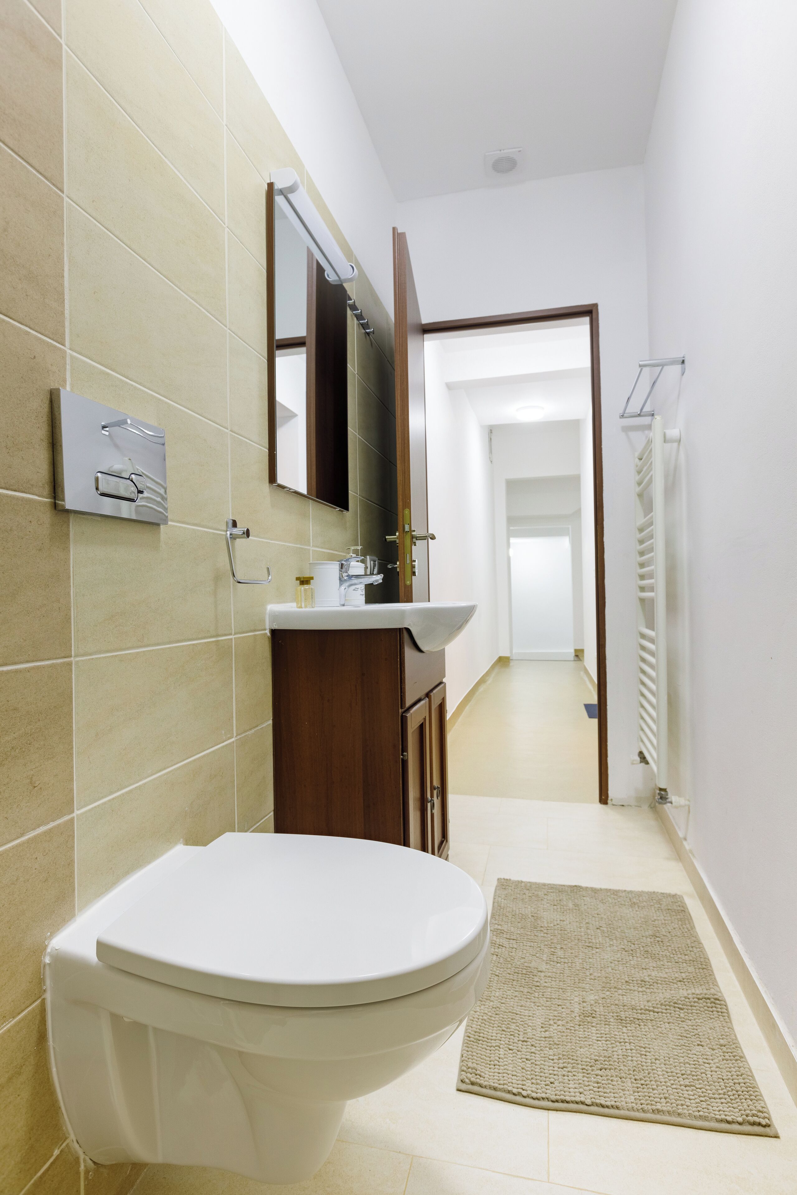 Une salle de bain équipée de toilettes, d’un lavabo, d’un miroir et d’un porte-serviettes.