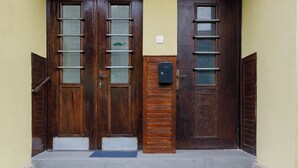 A building entrance with two wooden doors, a mailbox, and a set of concrete steps leading up to the entrance. - Modern Apartment (Brasov)