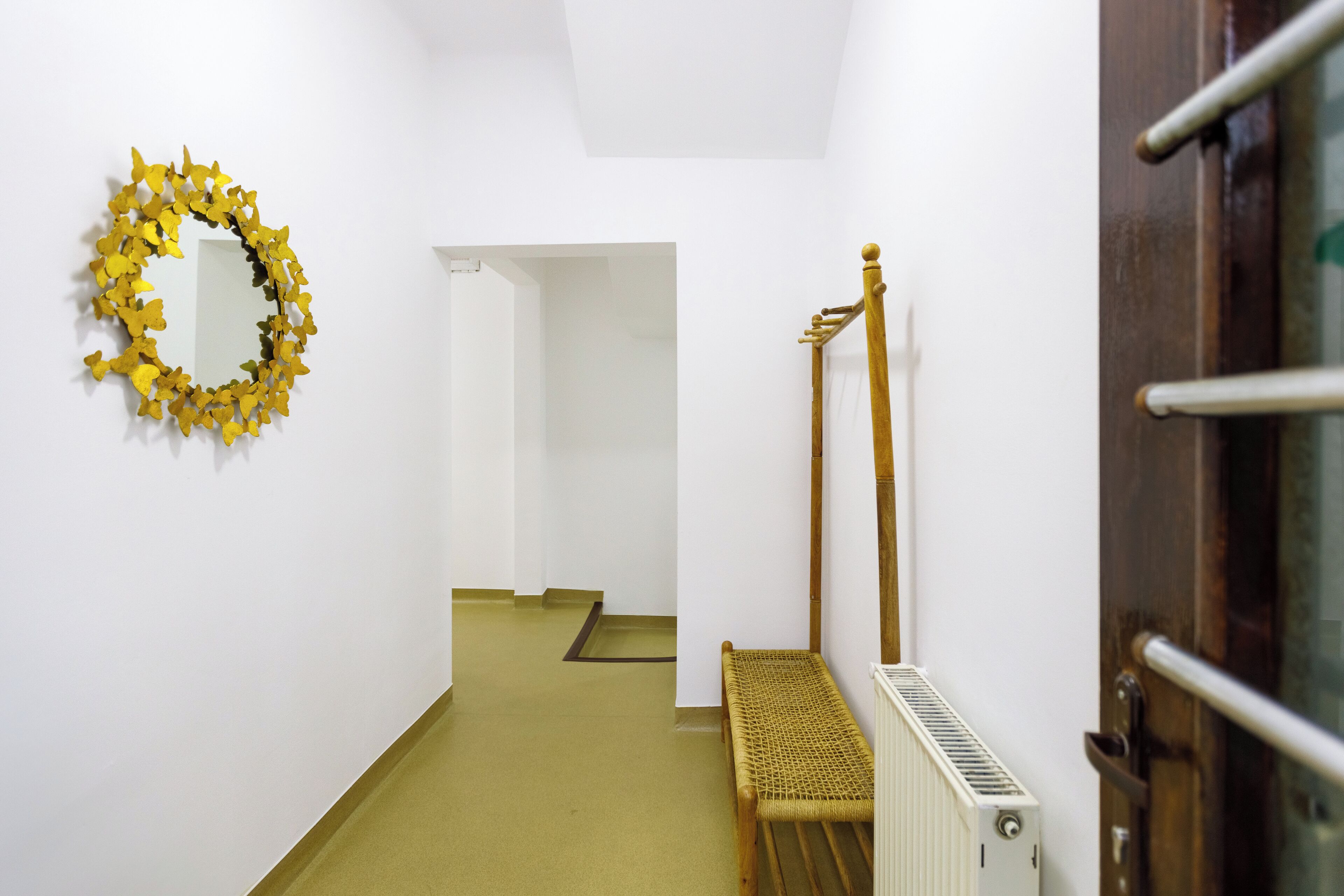 A narrow hallway with a wooden bench, a radiator, and a wooden door frame.
