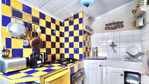 A kitchen with a checkered tile backsplash, a stove, a sink, and various utensils. - La Maisonette Cambon, Charme en Camargue (Saintes-Maries-de-la-Mer)