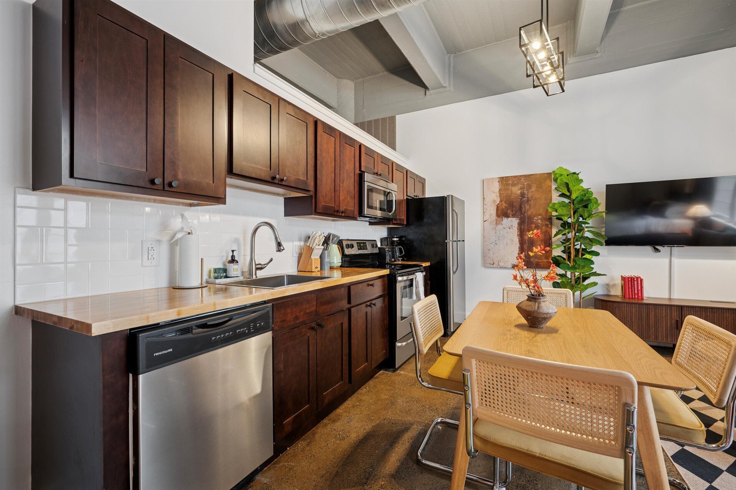 Una cocina moderna con armarios de madera oscura, electrodomésticos de acero inoxidable y una mesa de comedor de madera con dos sillas.