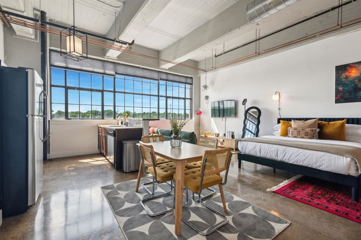 A modern, open-plan living space with a kitchen, dining area, and bedroom.