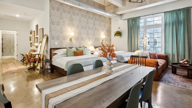 A modern hotel room with a large bed, a dining table, and a seating area. - Storehouse Lofts (Philadelphia)