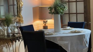 A dining area with a round table, two chairs, a chandelier, a lamp, and a mirror with a decorative frame. - Un Lugar Para Compartir en Familia (Allentown)