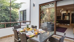 Comedor con sillas de mimbre y una mesa de vidrio dispuesta para el desayuno.