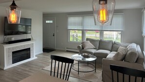 Uma sala de estar moderna com lareira, um sofá, uma mesa de centro e duas luminárias pendentes.
