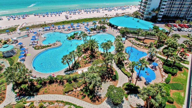 A resort with multiple swimming pools, a beach, and a tall hotel building. - Seabreeze Bliss @ Edgewater - 5th floor, private balcony, direct beachfront (Panama City Beach)