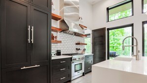 Een moderne keuken met donkere kastjes, een wit aanrechtblad en een inbouwoven.