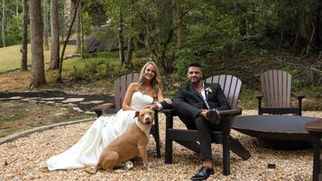 A couple seated on wooden chairs outdoors with a dog.