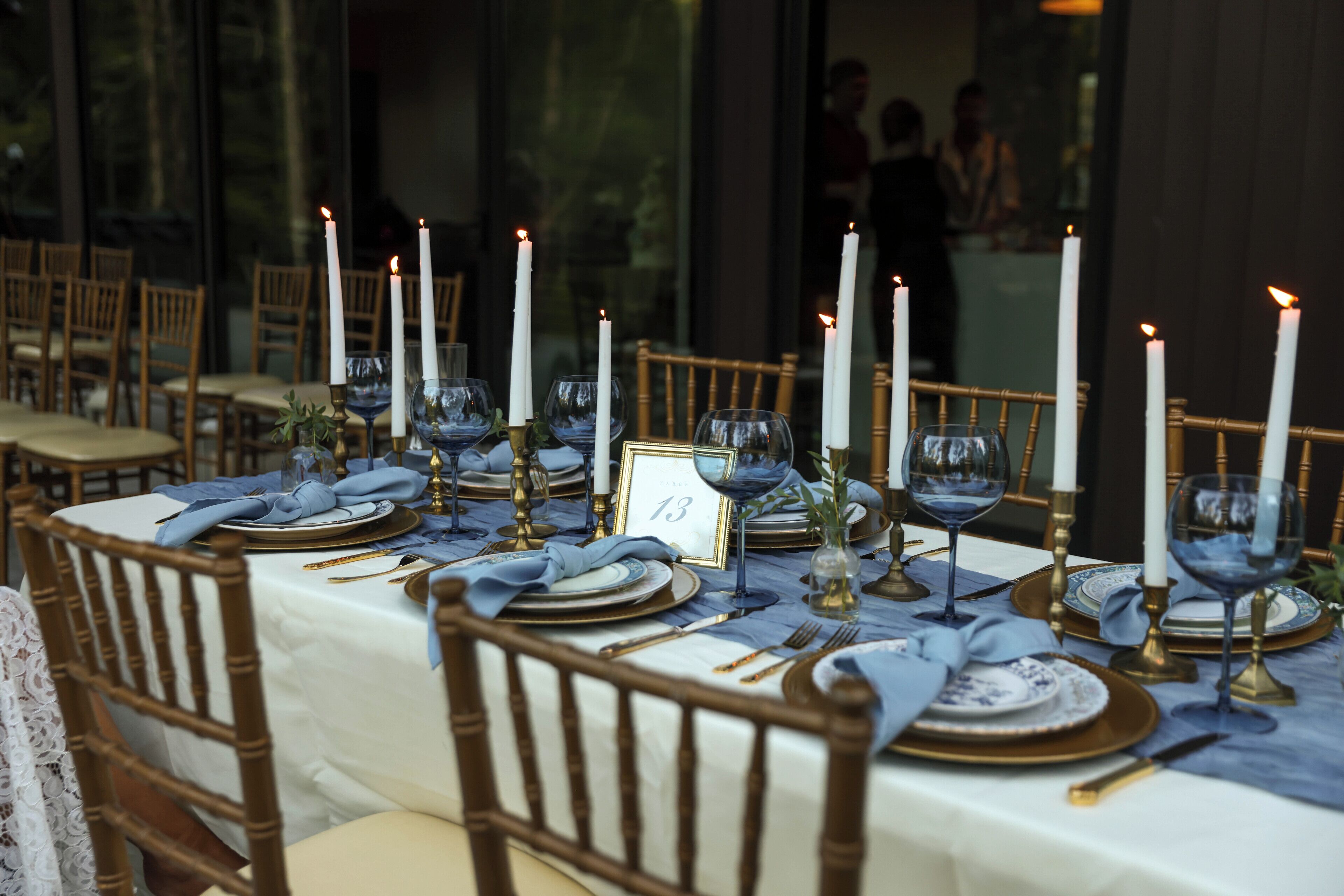 A table set with blue napkins, white candles, and gold and blue plates.