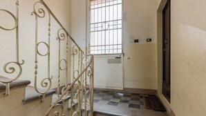 A staircase with ornate metal railings leading to a door with a barred window. - Studio Calari alle Mura by Wonderful Italy (Bologna)