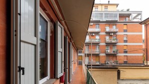 A narrow corridor with a brick wall on one side and a balcony on the other. - Studio Calari alle Mura by Wonderful Italy (Bologna)