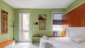 A bedroom with a bed, a bedside table, a coat rack, a door, and a window. - Studio Calari alle Mura by Wonderful Italy (Bologna)